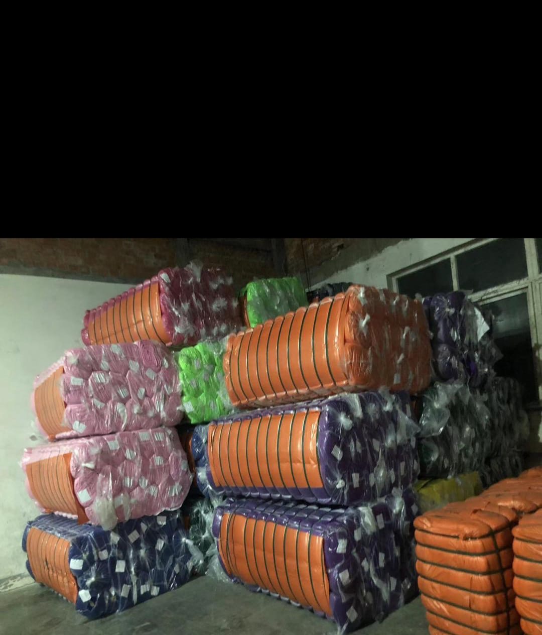 Warehouse bales of orange, pink and purple textile materials