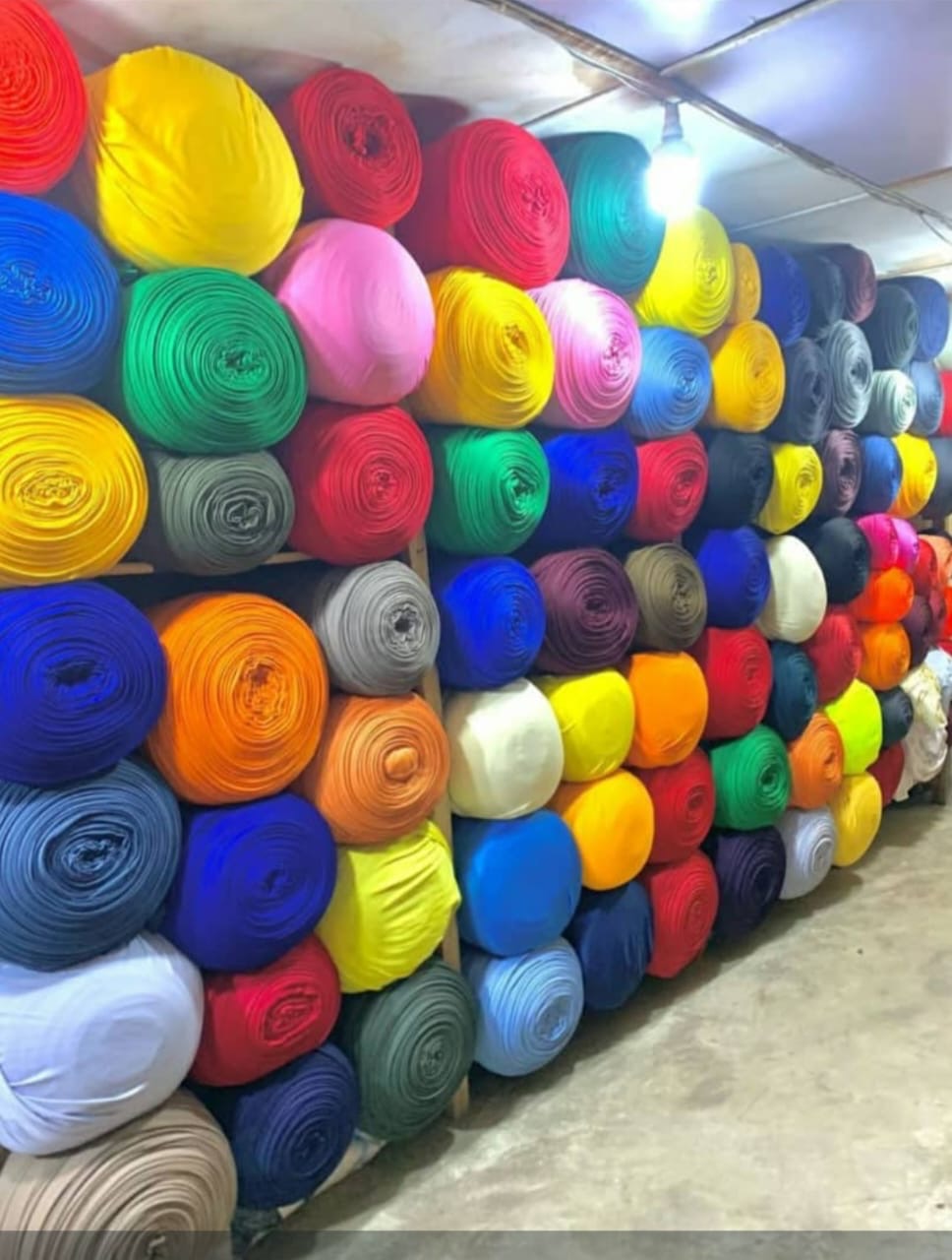 Aisle of stacked colorful fabric rolls in the Ceedar Planet warehouse